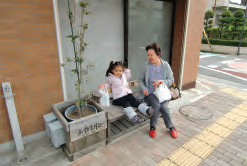 店舗前のベンチでくつろぐ歩行者
