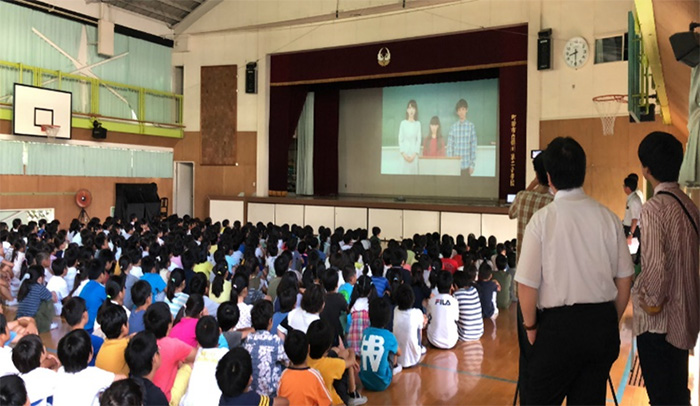 「防災集会」でDVD「洪水から身を守るには~命を守るための3つのポイント」を視聴する児童
