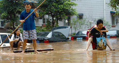 中国南西部の重慶市で、大雨で浸水した道路を渡る人々